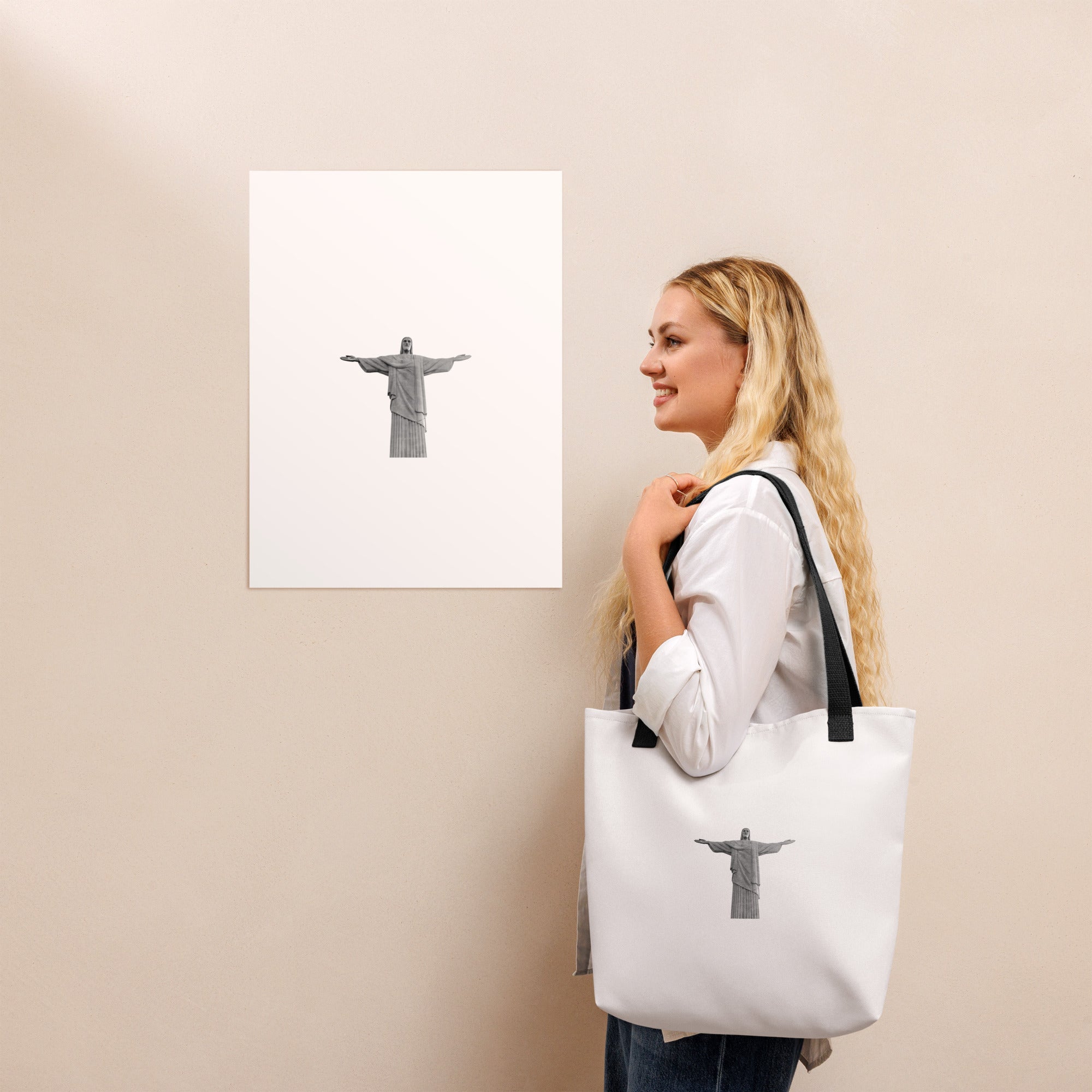 Woman carrying a Christ the Redeemer tote bag 15x15, standing near an art print of Christ the Redeemer.