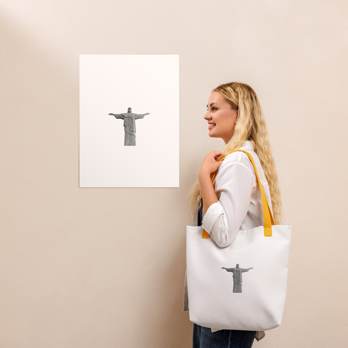 Woman carrying a Christ the Redeemer tote bag 15x15, standing near an art print of Christ the Redeemer.