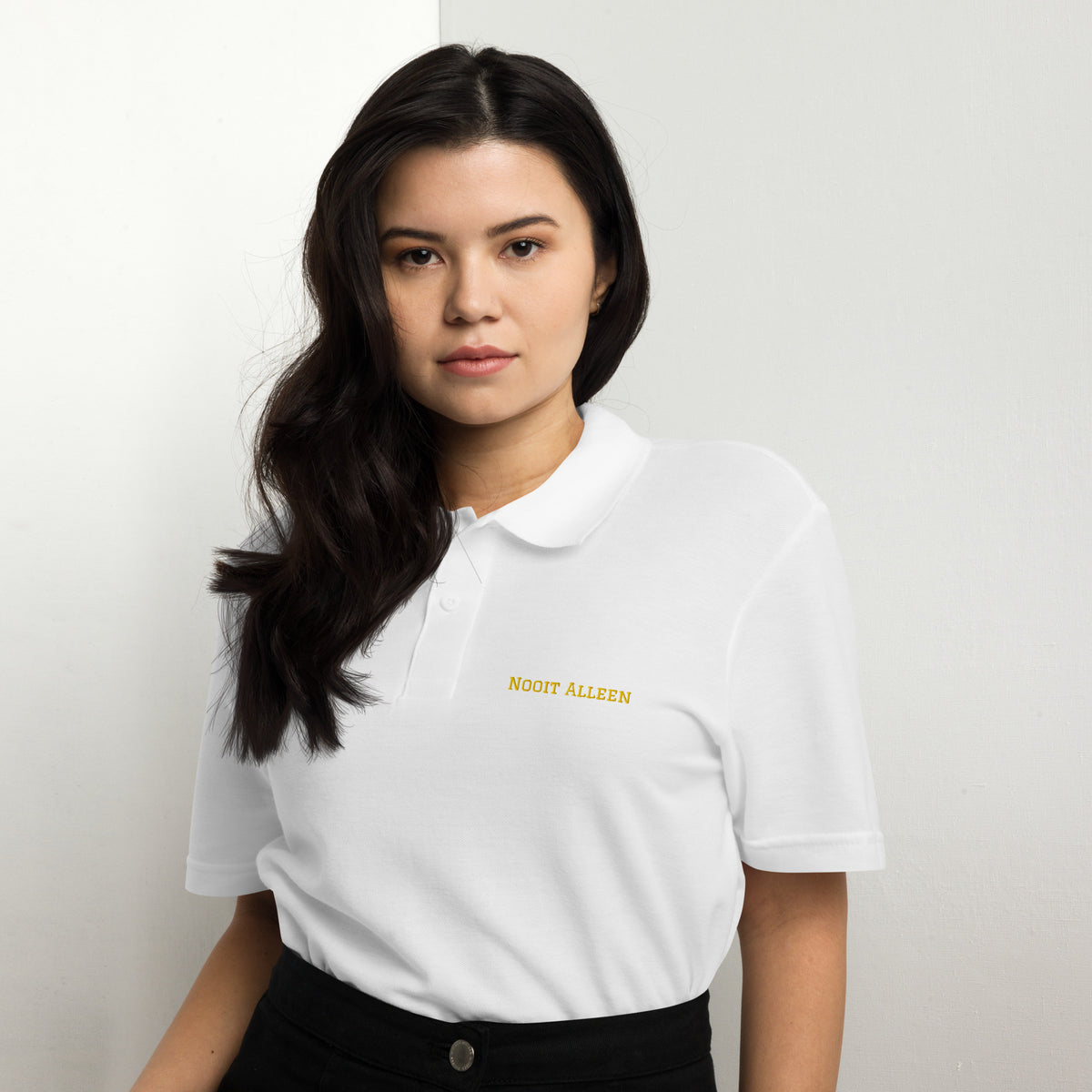 Woman wearing a white Nooit Alleen polo shirt with yellow text.